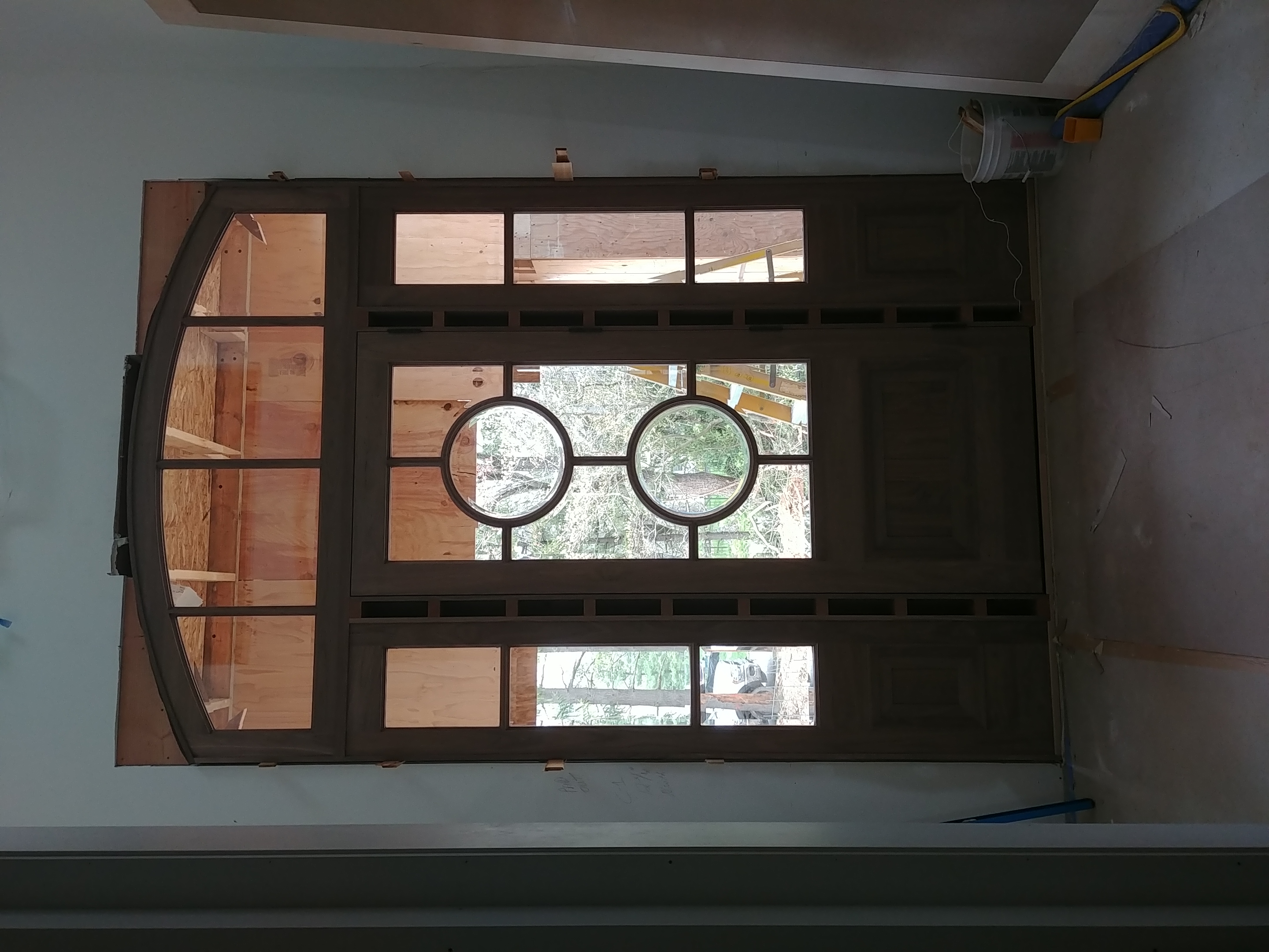 Custom arched entry door with paired oculus leaded-glass lights, on sawhorses in shop