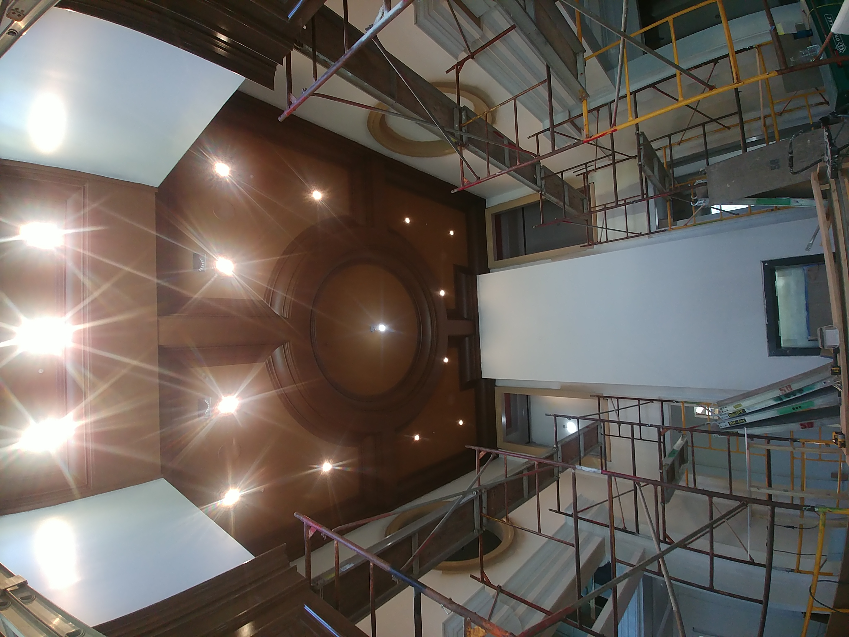 A coffered dome ceiling with multiple recessed lights, scaffolding still in place during install