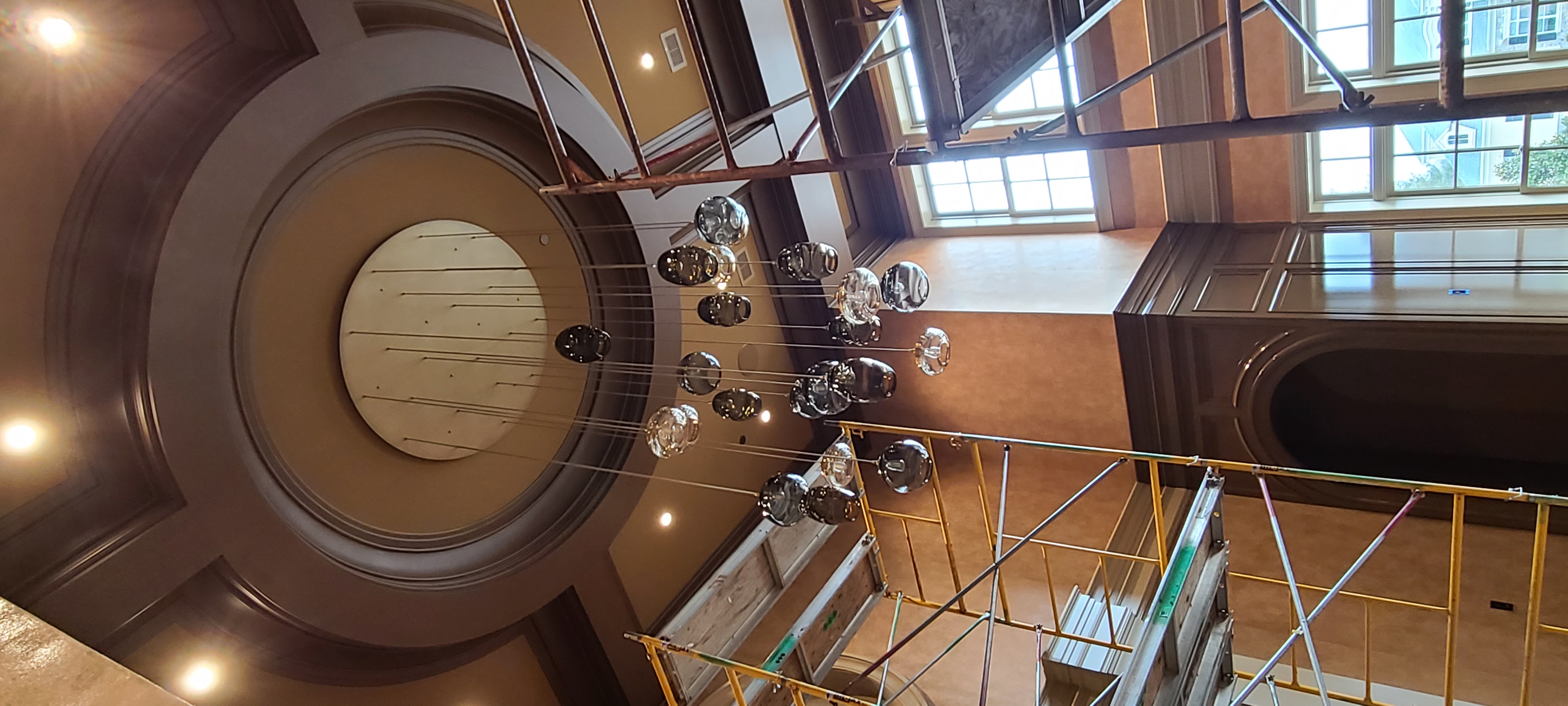 A coffered rotunda ceiling with a bubble-glass chandelier suspended below tall windows